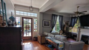 Ein geräumiges Wohnzimmer mit Kamin, einer Couch, einem Esstisch und einer Küchenzeile.