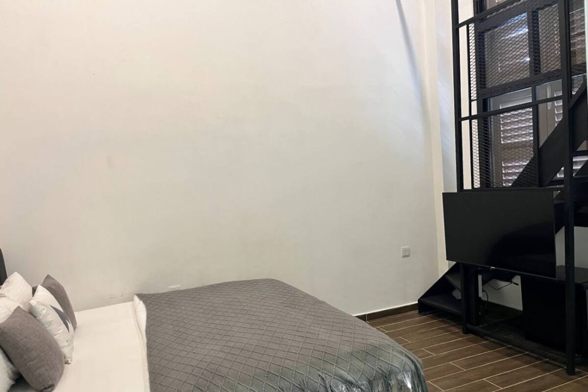 A bedroom with a bed, pillows, a TV, and a window.