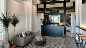 A reception area with a sofa, coffee table, and potted plants. - The Magazine Boutique Hotel (George Town)