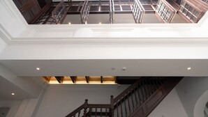 A multi-level interior with a central staircase, white walls, and a skylight. - The Magazine Boutique Hotel (George Town)