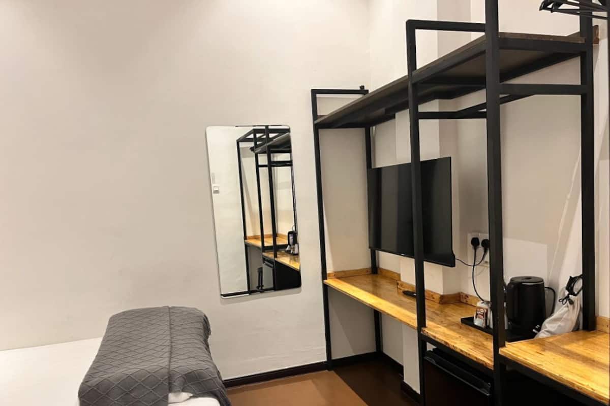 A small, compact room with a bunk bed, a desk with a computer, and a mirror.