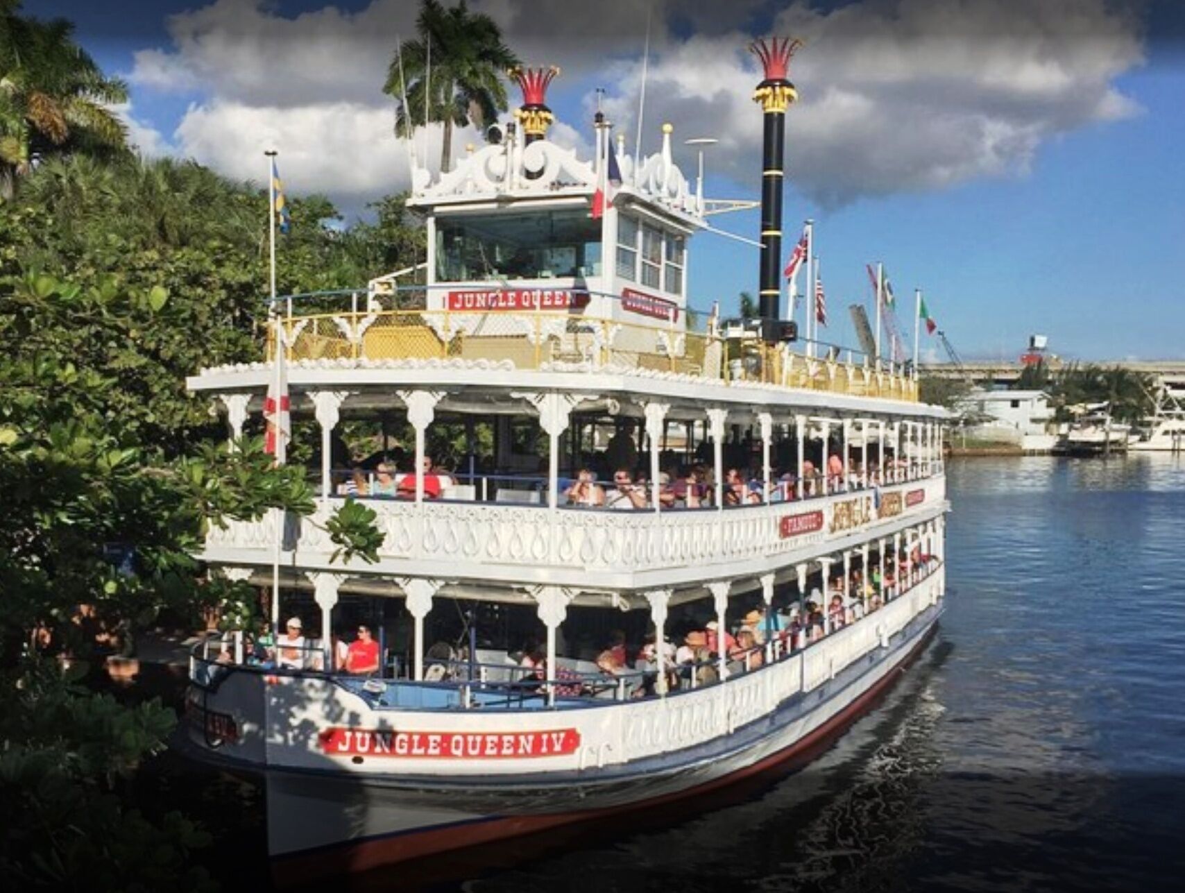 Ett flodkryssningsfartyg som heter ”Jungle Queen IV”, med flera däck och många passagerare.
