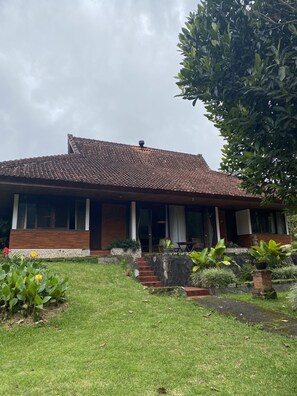 A house with a tiled roof, a stone foundation, and a front porch with steps leading to a door.