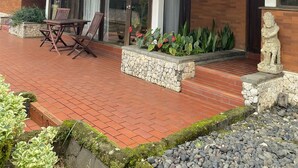 Un espacio de estar al aire libre cubierto con una mesa y sillas, una jardinera de piedra con plantas y una estatua.