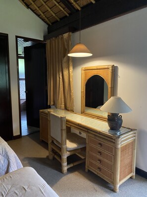 A wooden desk with a mirror, a lamp, and a drawer.