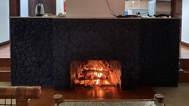 Una cocina moderna con chimenea de piedra, un televisor de pantalla plana montado sobre ella y techo de bambú.