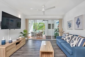 Relax in this stylish living room with a flat-screen TV, comfortable sofa, and wicker chair.
