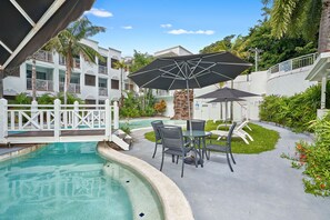 Relax by the serene pool surrounded by lush greenery and comfortable lounge seating.