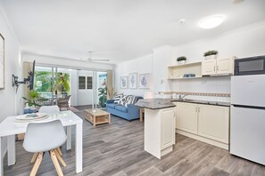 Enjoy a comfortable living area with a sofa and dining table for four, plus a kitchen with appliances and a convenient island with sink.