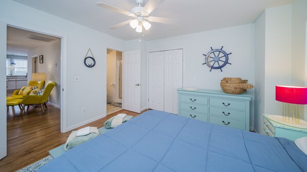 Une chambre à coucher avec un lit, un ventilateur de plafond, une commode et une chaise.