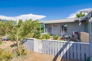 A residential property with a white exterior, a visible address number, a fenced backyard, and a patio area with outdoor furniture.