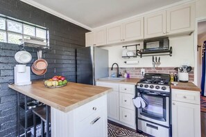 A kitchen with a wooden countertop, a refrigerator, a stove, and a microwave. - Chic, Playful Boho Bungalow Near Everything! (La Mesa)
