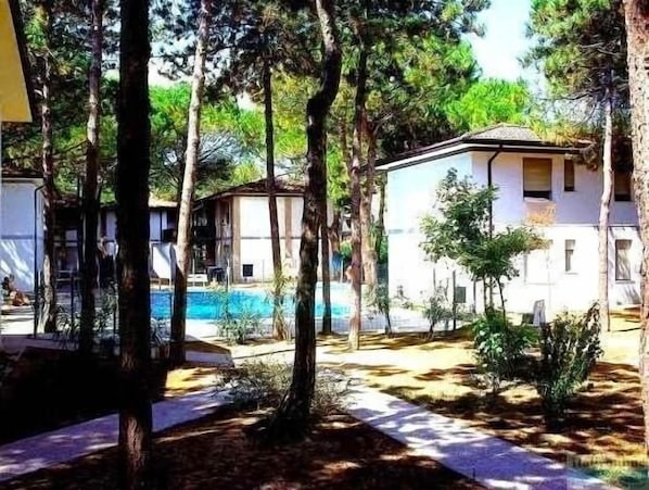 A resort with a swimming pool surrounded by trees and a few buildings.