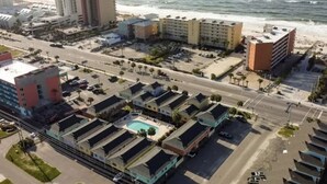 An aerial view of a coastal hotel with multiple buildings, a parking lot, and a swimming pool. - Convenient to everything! Only steps to the beach. (Gulf Shores)