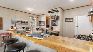 Una cocina con encimera de madera, taburetes de bar, un refrigerador y diversos utensilios de cocina.
