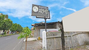 Een bord voor Hotel Arimbi met een goed overzicht van de omgeving, inclusief een weg en een gebouw.