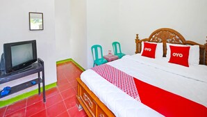 Een hotelkamer met een bed, een televisie op een standaard en twee stoelen.