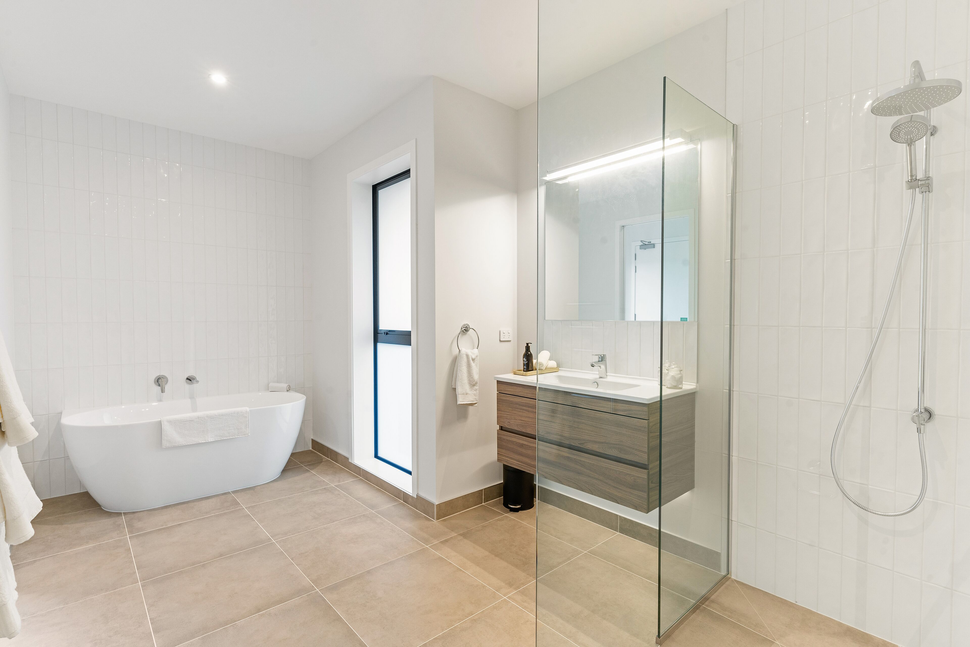 A modern bathroom with a freestanding bathtub, a glass-enclosed shower, and a vanity with a mirror.