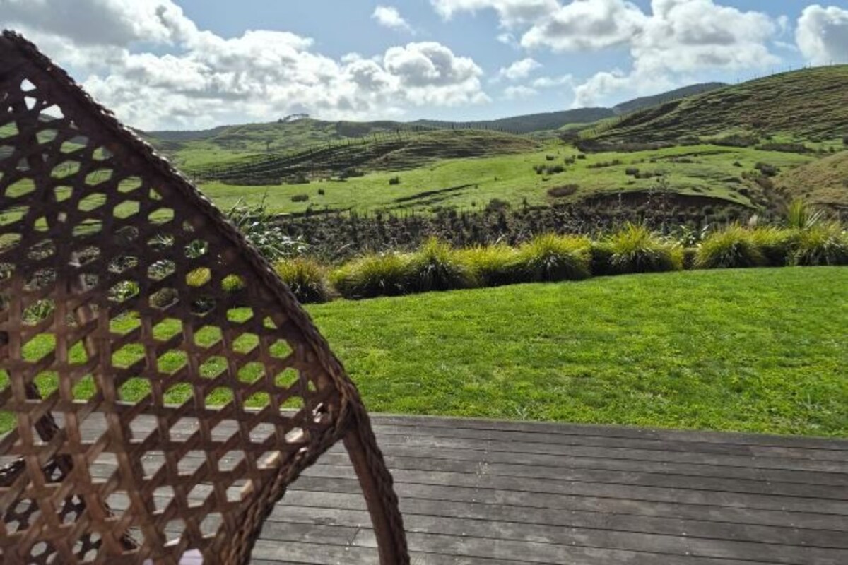 A view of a green landscape with rolling hills and a wooden deck.