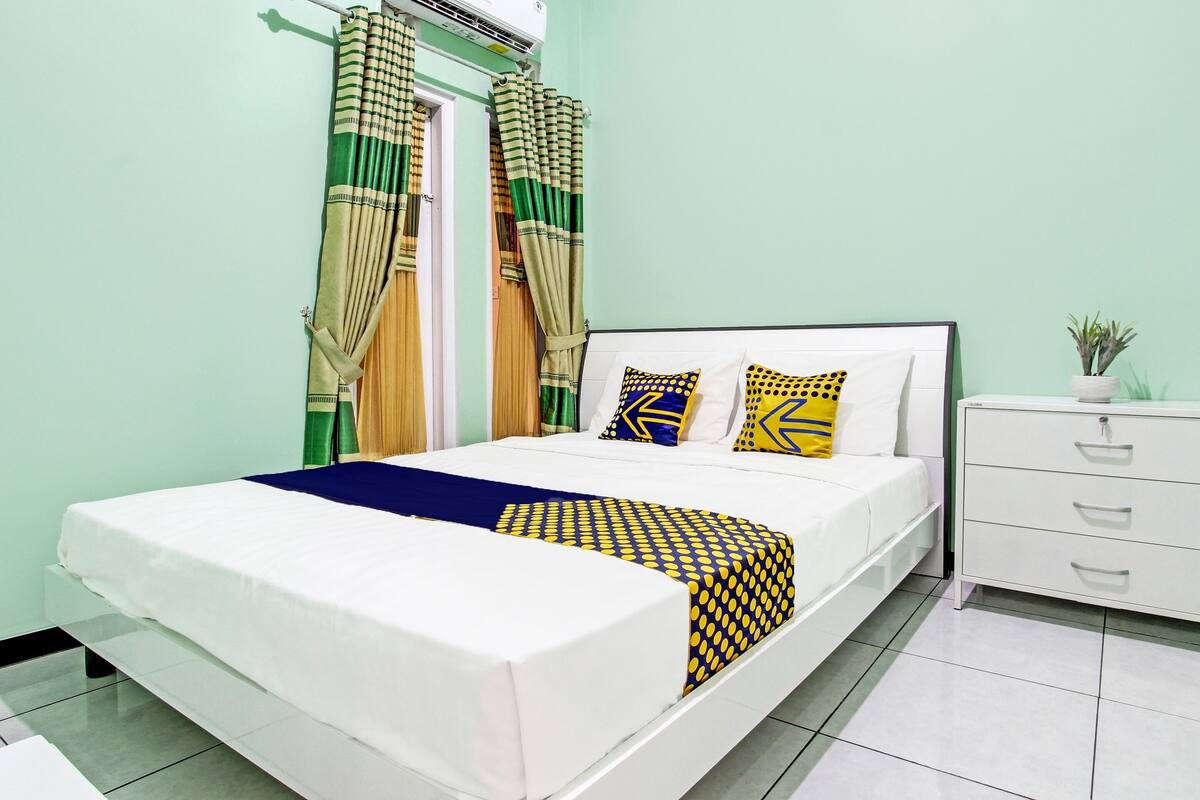 A neatly made bed with a white mattress and blue and yellow patterned bedspread.
