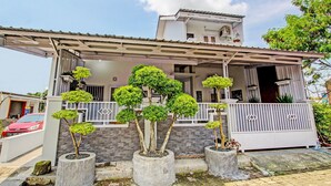 A two-story house with a covered porch, potted trees, and a gated entrance. - Hotel O Homestay Grand Mahkota Permai Syariah (Muncar)