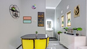 A modern kitchen with a round dining table, yellow chairs, and a white cabinet. - Hotel O Homestay Grand Mahkota Permai Syariah (Muncar)
