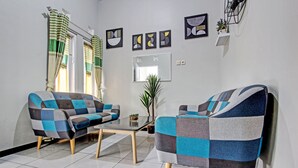 A living room with a sofa and armchair, a coffee table, and a mirror on the wall. - Hotel O Homestay Grand Mahkota Permai Syariah (Muncar)