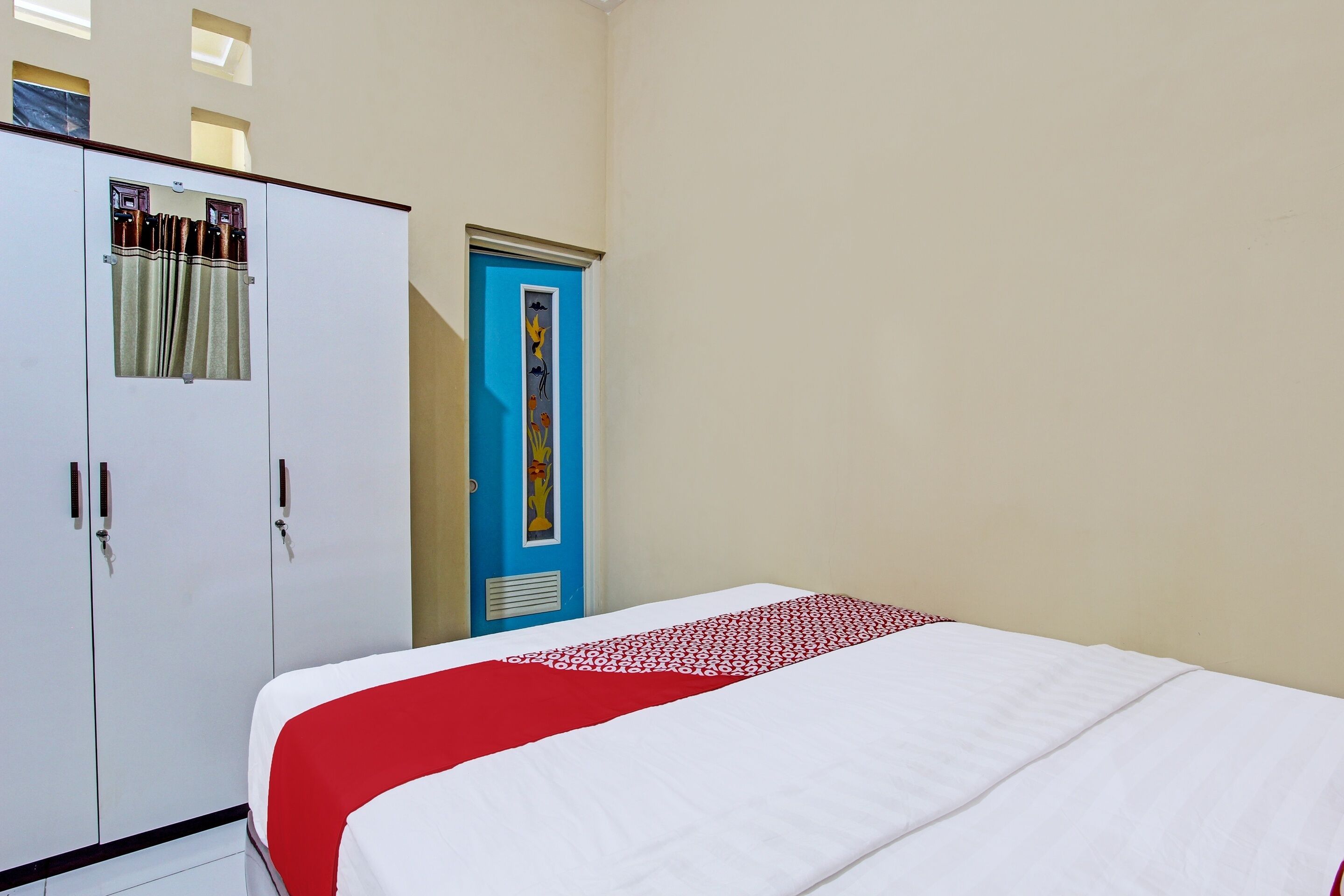A bedroom with a bed, a wardrobe, and a door.