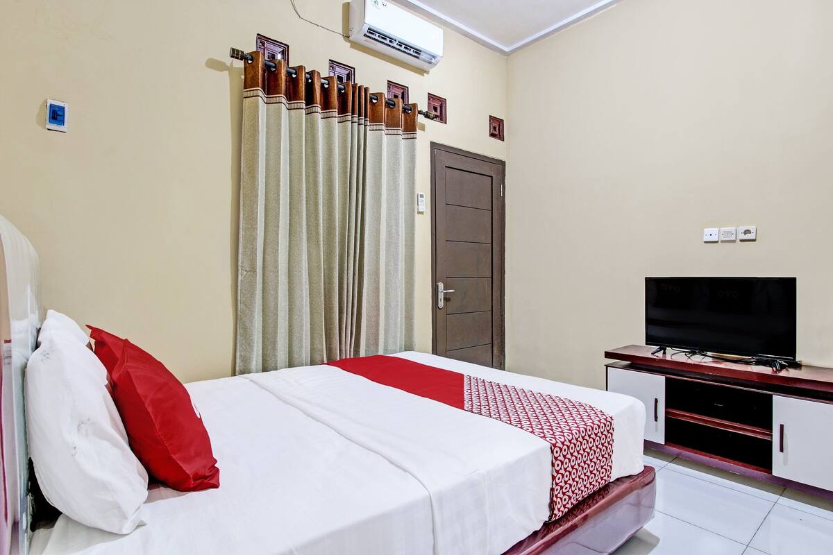 Een hotelkamer met een bed, een televisie, een kledingkast en airconditioning.