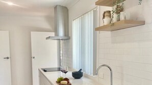 Een moderne keuken met witte kastjes, een roestvrijstalen spoelbak en een inbouw afzuigkap.