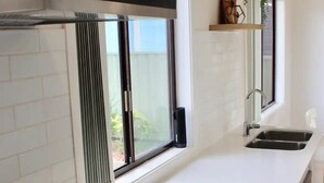 Een moderne keuken met een zwart inductiekookveld, een raam met zonwering en een inbouwspoelbak.