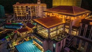 Un hotel de varios pisos con piscina, varios balcones y una fachada bien iluminada.