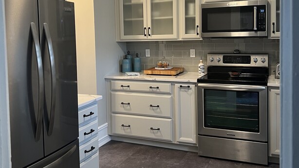 A modern kitchen with stainless steel appliances, white cabinetry, and a built-in oven.