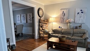 A cozy living room with a wooden coffee table, a beige sofa, and a dining area with a chair and table.