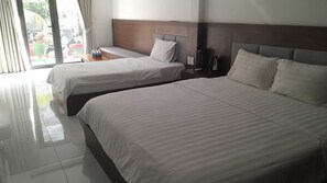 A hotel room with two beds, a wooden headboard, a nightstand, and a view of the outside. - Coastal Village PQ (Phu Quoc)