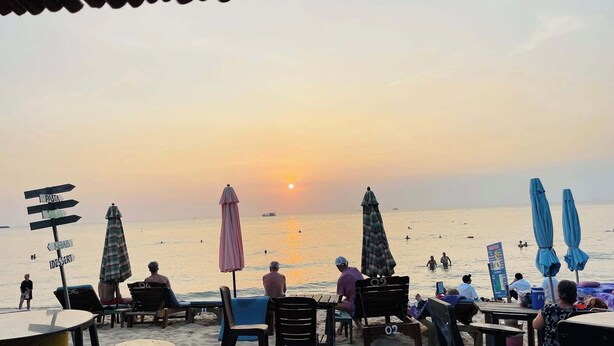 A beachside restaurant with outdoor seating and umbrellas, overlooking the sea during sunset. - Coastal Village PQ (Phu Quoc)