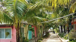 A narrow, tree-lined street with buildings on either side. - Coastal Village PQ (Phu Quoc)