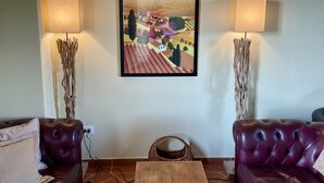 Um quarto com dois sofás de couro, uma mesa de centro de madeira e uma obra de arte emoldurada na parede.