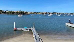 A marina with multiple boats docked, a sandy beach, and a clear blue sky.