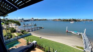 A waterfront property with a swimming pool, a deck, and a view of the marina and city skyline.