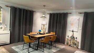 A dining area with a wooden table, four chairs, a rug, a lamp, and a wall-mounted picture.