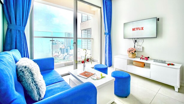 A modern living room with a large window, a flat-screen TV, and a white entertainment unit.