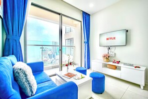 Una sala de estar moderna con un ventanal grande, un televisor de pantalla plana y un mueble blanco para equipo de entretenimiento.