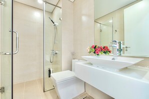 A modern bathroom with a glass shower enclosure, a white toilet, and a vanity with a sink and mirror. - MILLENIUM - Luxury Central Apartments (Ho Chi Minh City)