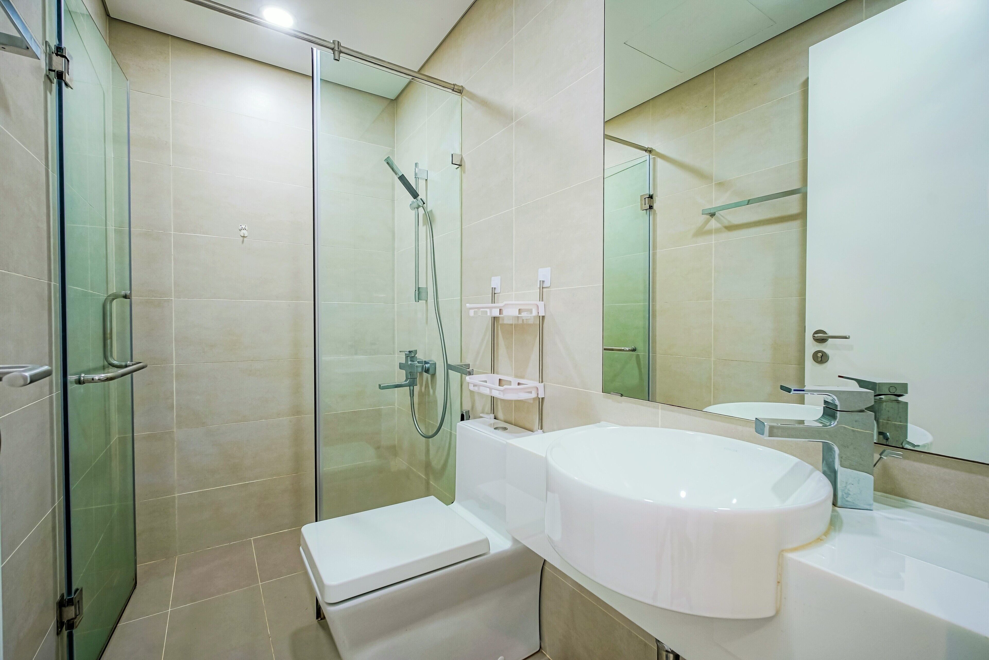 A modern bathroom with a glass-enclosed shower, a white sink, and a toilet.