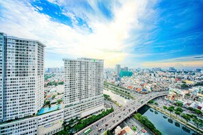 A high-rise hotel with multiple floors, a swimming pool, and a view of the cityscape and river.