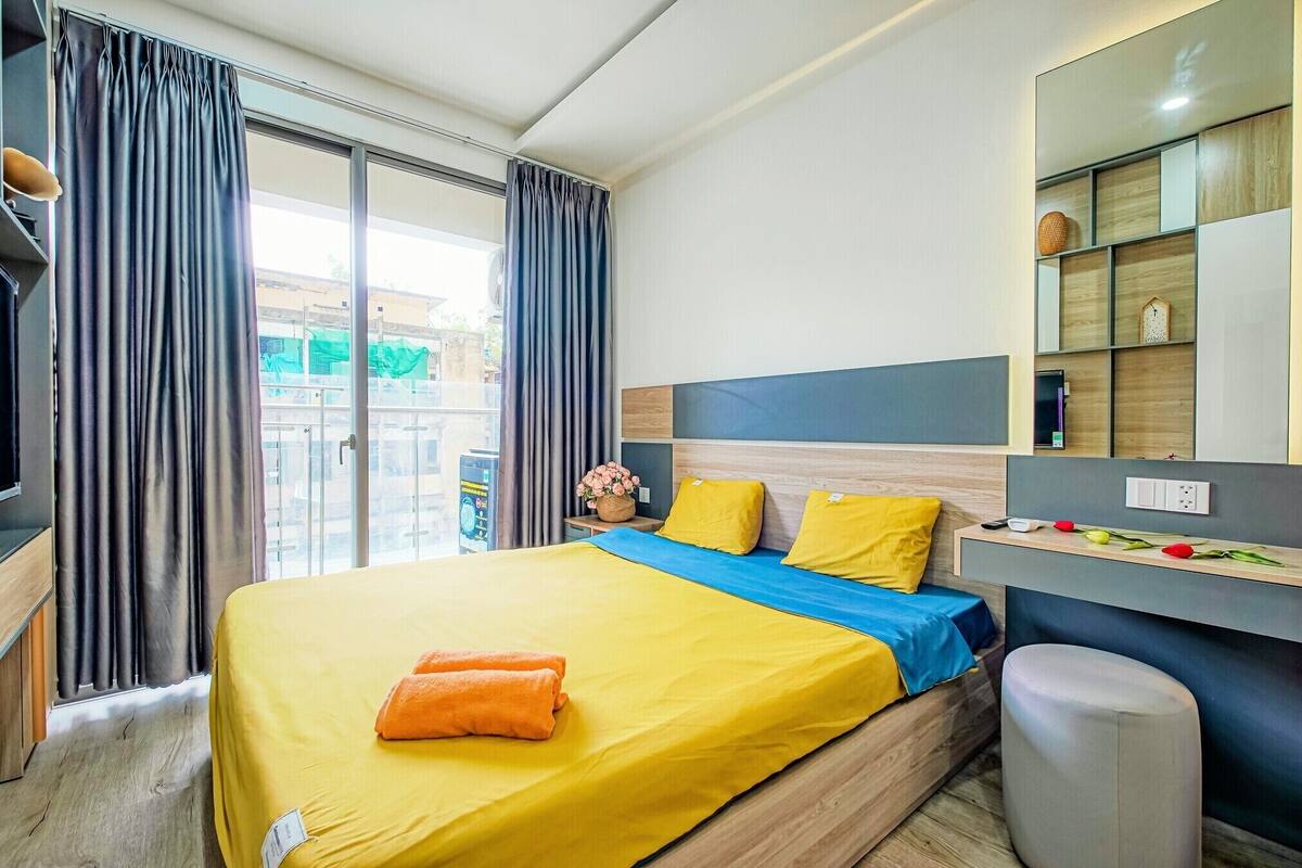 A hotel room with a large bed, a desk, and a view of the outside.