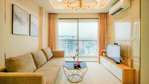 A modern living room with a sofa, a hexagonal coffee table with a vase, a flat-screen TV, and a balcony with a city view.