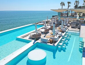 A poolside area with lounge chairs, umbrellas, and a view of the sea. - Sundance Dayclub Hua Hin (Hua Hin)