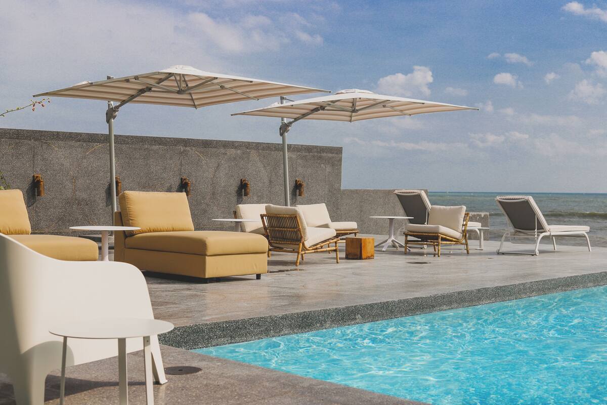 A poolside area with lounge chairs, umbrellas, and a view of the ocean.